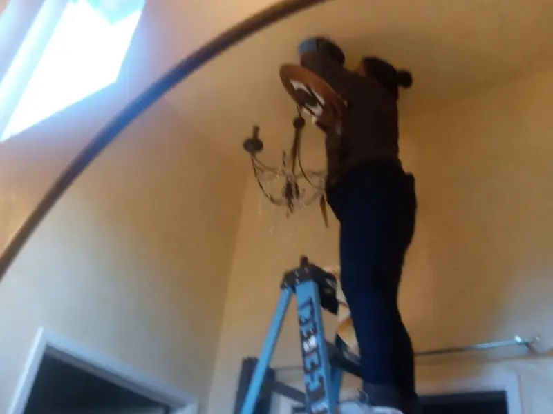 Electrician installing a chandelier in a New Castle residence